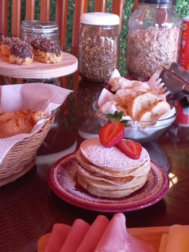 a stack of pancakes on a plate with a strawberry on top at Refugio maná in Campos do Jordão