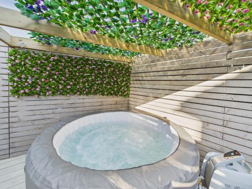 a jacuzzi tub in a backyard with flowers at Corner House- hot tub and outdoor fireplace in Herstmonceux