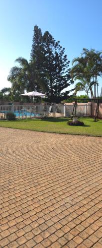 a brick road with a fence and trees in a park at Aloe Self Catering in Port Shepstone