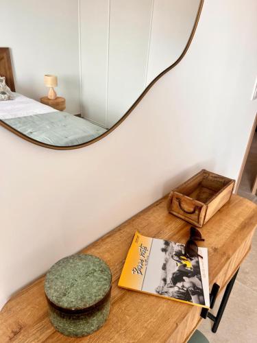 une table avec un miroir, un livre et un tabouret dans l'établissement Appartement CASA VISTA splendide vue sur le Golfe, à Porto-Vecchio