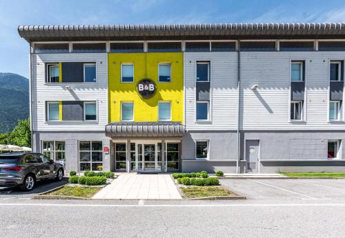 a yellow and white building with a car parked in front at B&B HOTEL Saint Jean De Maurienne in Sainte-Marie-de-Cuines