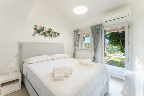 a white bedroom with a white bed and a window at Villa Stella Lux in Chia