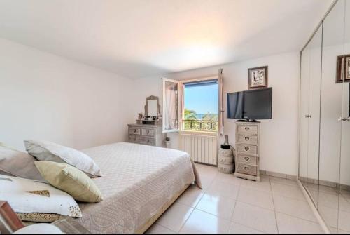 une chambre avec un lit, une télévision et une fenêtre dans l'établissement Face à la mer, à Théoule-sur-Mer