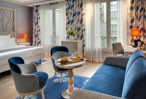 une chambre d'hôtel avec un lit et un canapé bleu dans l'établissement Rochester Champs Elysees, à Paris
