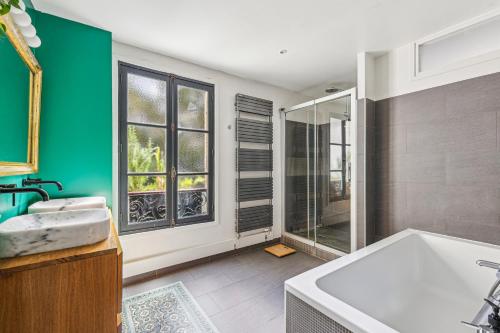 une salle de bain avec baignoire et douche en verre dans l'établissement Familial appartement 8 personnes by Weekome, à Paris