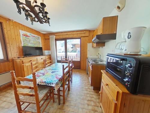- une cuisine avec une table, des chaises et une cuisinière dans l'établissement Studio cabine 5 pers, proche patinoire et pistes, Le Grand-Bornand - FR-1-241-45, au Grand-Bornand