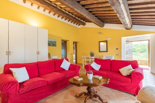 a living room with two red couches and a table at Masseria del bosco Poderuccio in Chianciano Terme