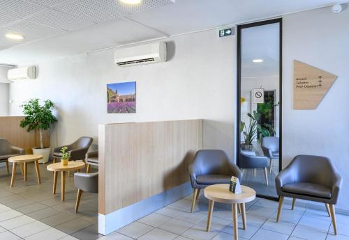 a waiting room with chairs and tables at B&B HOTEL Orange in Orange