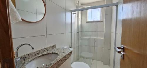 a bathroom with a sink and a toilet and a mirror at COPFL0109 - Condomínio Residencial Ilha de Maiorca in Salvador