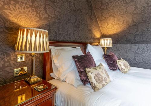 a bedroom with a bed with pillows and two lamps at Knockinaam Lodge in Portpatrick