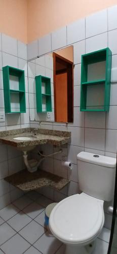 a bathroom with a white toilet and green cabinets at Flat Casa Taíba 2003 in Taíba