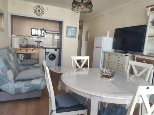 un salon avec une table et une cuisine dans l'établissement Appartement T2 450m de la plage des demoiselles, avec garage et possibilité de vélos à 950m de la rue piétonne, à Saint-Hilaire-de-Riez