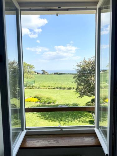 une fenêtre avec vue sur un champ vert dans l'établissement Maison familiale vue mer douceur à Clohars, à Clohars-Carnoët
