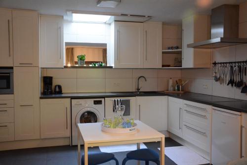 a kitchen with white cabinets and a table with a dishwasher at Vakantiewoning Het Wielje Maasland in Kinrooi