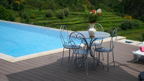 a table with chairs and a vase of flowers on a deck at A CASINHA DO CARREIRAS in Barroselas