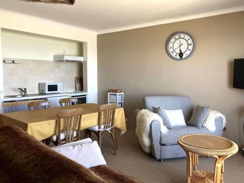 - un salon avec une table et une horloge murale dans l'établissement Anemone - Saint Hilaire de Riez, à Saint-Hilaire-de-Riez