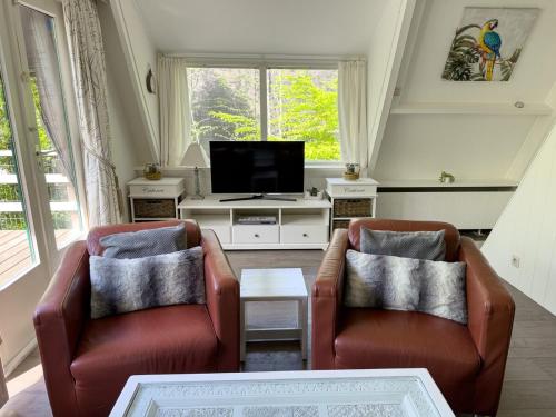 a living room with two chairs and a tv at Chalet Sumo in Durbuy