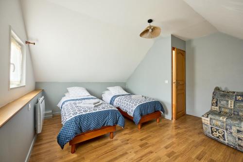 a bedroom with two beds and a chair at Entre Histoire et Marais - Proche Plage in Carentan