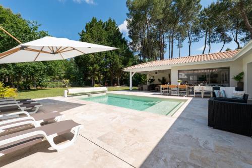 une piscine avec des chaises et un parasol à côté d'une maison dans l'établissement Sunny Villa Nature, à Grayan-et-lʼHôpital