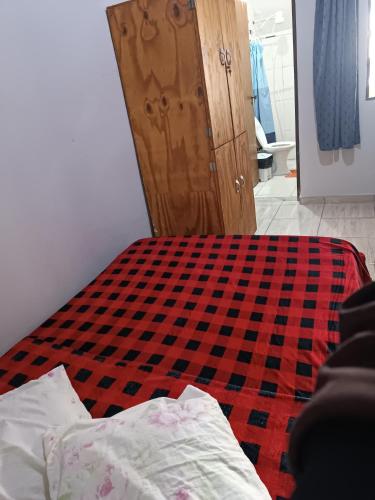 a bedroom with a bed with a red and black checkered floor at Hostel do Papai 3 in Lavras