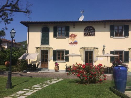 a large white house with black shuttered windows at Residence Prunali in Massarosa