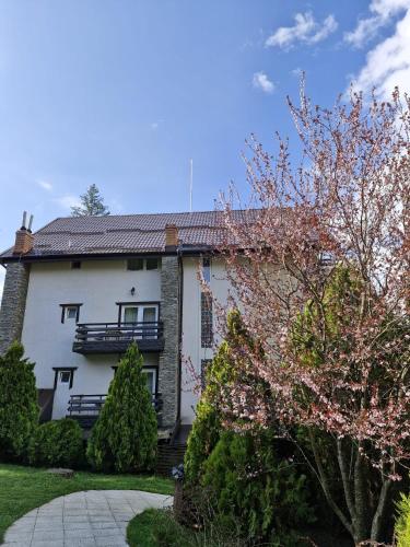 a white house with a balcony and trees at Hotel Piatra Soimului in Sinaia