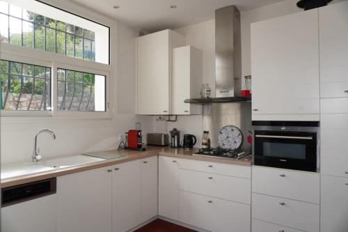 une cuisine blanche avec des armoires blanches et une fenêtre dans l'établissement Villa de charme, vue mer, baignée de soleil, à Grasse