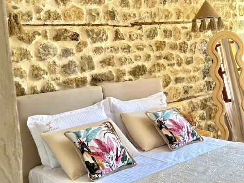 a bed with pillows on it with a stone wall at Casa Palma Boutique Hotel in Vlorë