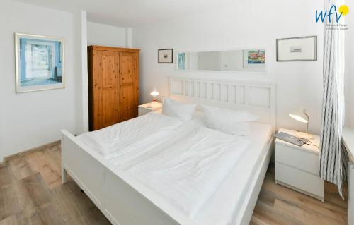 a large white bed in a white bedroom at Ferienhaus Caterlieschen Ferienwohnung 1 in Juist