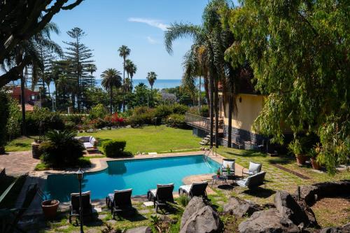 a swimming pool with chairs and the ocean in the background at Silvanae Pool Villa in Aci Castello