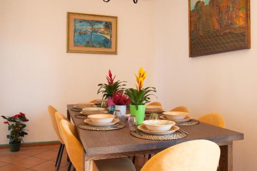 a dining room table with chairs and plates and flowers at Silvanae Pool Villa in Aci Castello