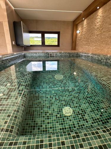 a swimming pool with a green tiled floor at Pensiunea Andres in Sovata