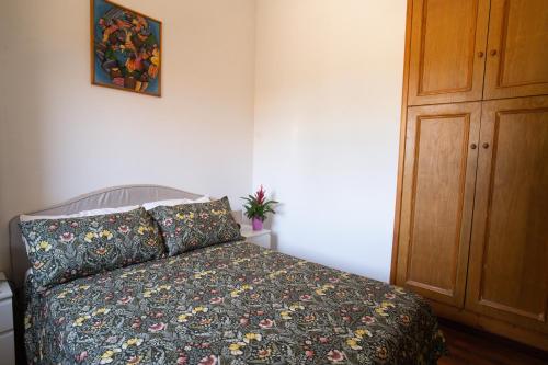 a bedroom with a bed with a floral bedspread and a wooden cabinet at Silvanae Pool Villa in Aci Castello