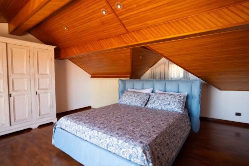 a bedroom with a blue bed with a wooden ceiling at Silvanae Pool Villa in Aci Castello