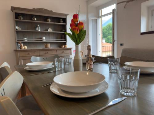 a dining room table with plates and flowers on it at Casa Valeria - a due passi dal Traghetto in Cernobbio