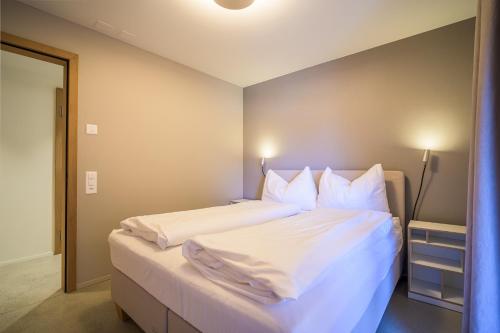 a bedroom with a bed with white sheets and pillows at Edelweiss Ferienwohnung, Crap da Flem in Flims