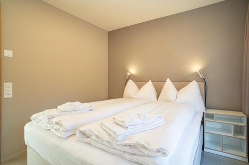 a white bed with towels on top of it at Edelweiss Stenna Cavorgia in Flims
