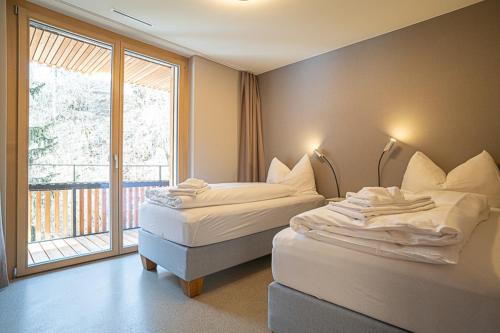 two beds in a room with a large window at Edelweiss Stenna Cavorgia in Flims