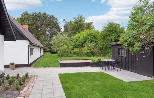 a garden with a patio with a table and a bench at Lovely Home In Nykøbing Sj With Kitchen in Nykøbing Sjælland
