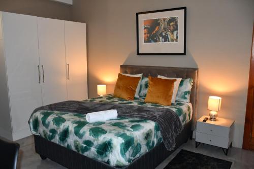 a bedroom with a bed with a green and white comforter at Setlhoa one bed apartment in Gaborone