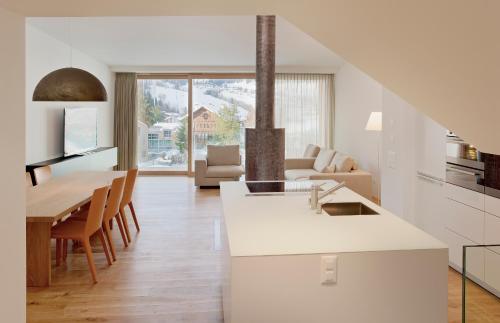a white kitchen and living room with a table and chairs at Edelweiss La Cerise in Flims