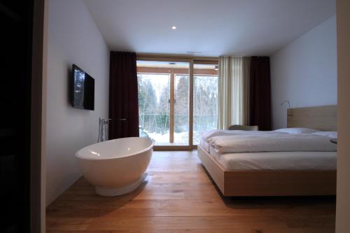 a bedroom with a tub and a bed and a window at Edelweiss La Cerise in Flims