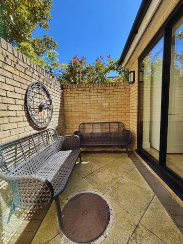 two benches sitting on a patio next to a brick wall at Bright Mews House with Garage in Heart of Cambridge in Cambridge