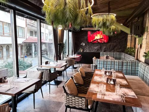 a restaurant with wooden tables and chairs and windows at SNOW PEAK TODORKA AND VIHREN APARTAMENT /NEXT TO THE LIFT/ 7 PERSONS/ in Bansko