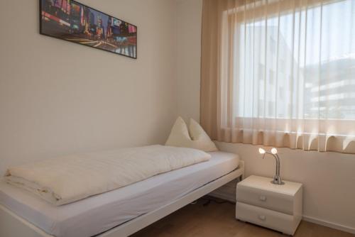 a white bedroom with a bed and a window at Edelweiss Casa Cassons in Flims