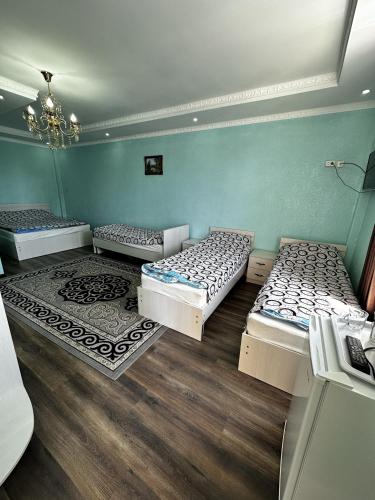 three beds in a room with blue walls and wooden floors at Yasina in Bosteri