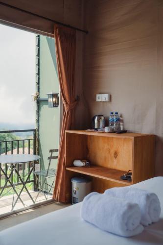 a bedroom with a bed and a balcony at Mesari Hill Glamping in Bedugul