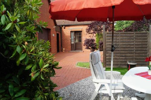 a patio with a table and a red umbrella at Ferienwohnung de Buhr, 95106 in Rhauderfehn