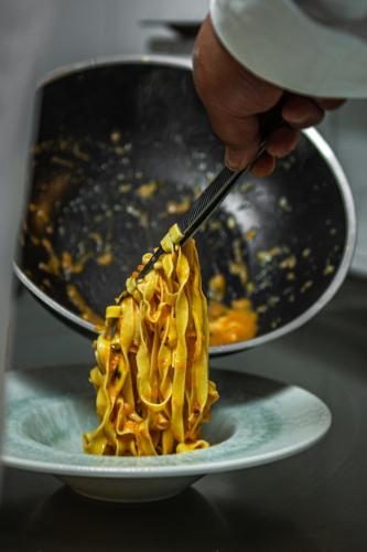 a person holding a utensil over a plate of pasta at Nest Beach Bungalows Datça in Datca
