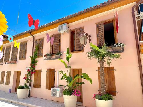 a pink building with wooden shuttered windows and plants at Casa Palma Boutique Hotel in Vlorë